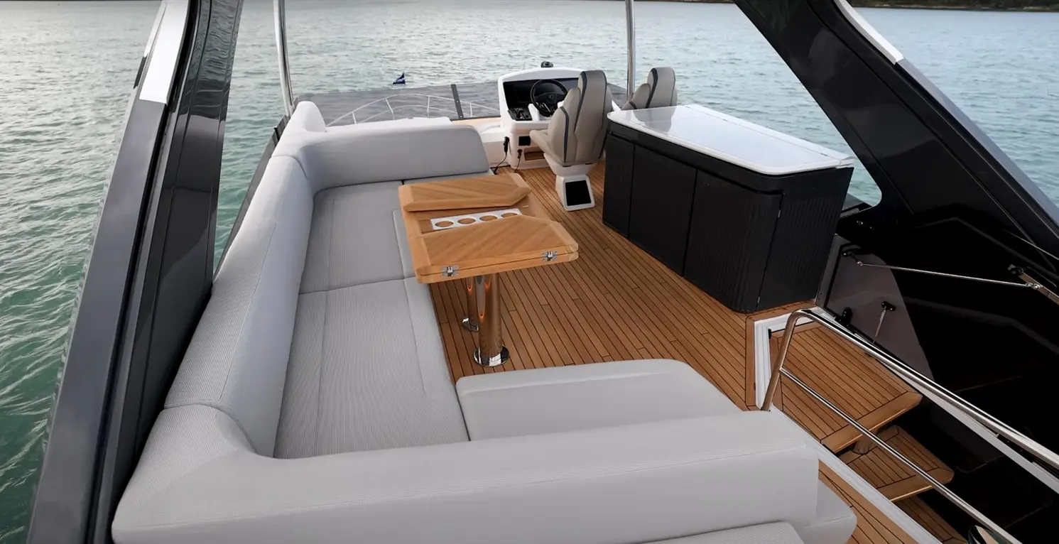 Luxurious boat interior features a spacious lounge, wooden table, pilot station, and ocean view, highlighting modern design.